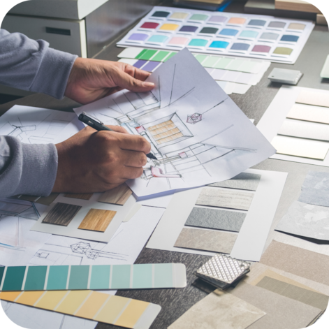 Hands holding a pencil and piece of paper with a sketch of a building on it.